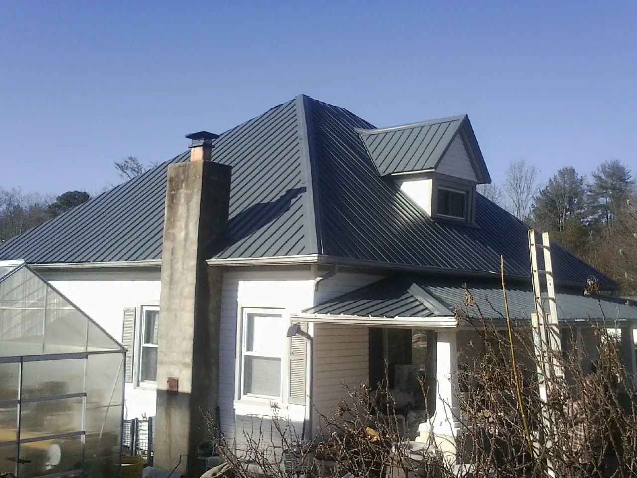 Dark blue standing seam metal roof on a white farmhouse with dormer — Slate & Tile Roof Repair by Roofing Brothers in Scales Mound