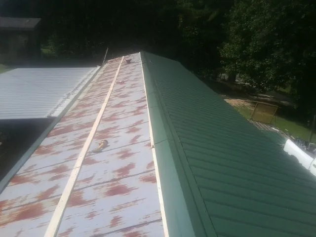 Old rusted panels beside newly installed green metal roofing — Wind Damage Roof Repair by Roofing Brothers in Scales Mound