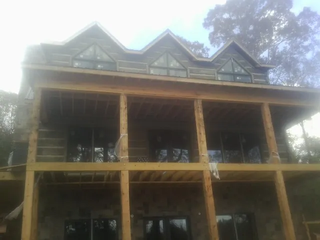 Dormers and porch framing on a large log home under construction — Roof Coating work by our crew in Scales Mound