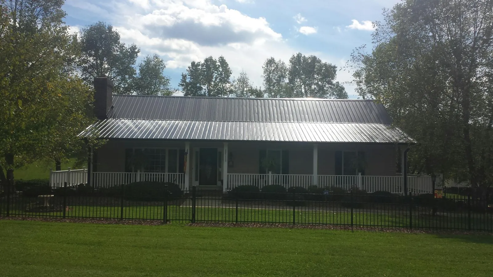 Gray metal roof on a brick ranch with a full width front porch — Gutter Guard Installation work by our crew in Scales Mound