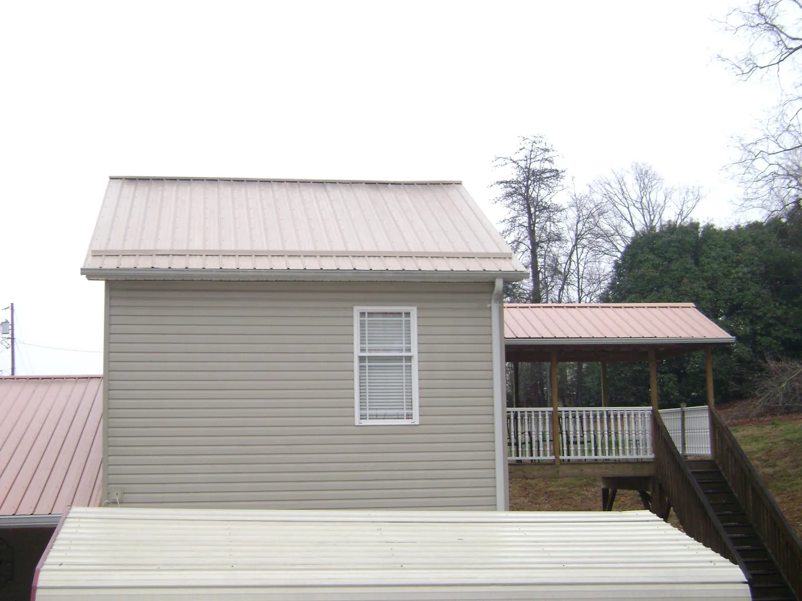 Tan metal roofs on a two story addition and attached porch, from a Roof Replacement job in Scales Mound