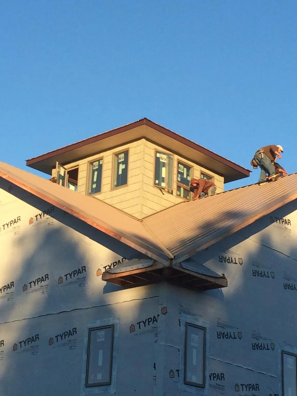 Roofers working around a rooftop cupola on a new metal roof at sunset — Roof Waterproofing in Scales Mound by Roofing Brothers